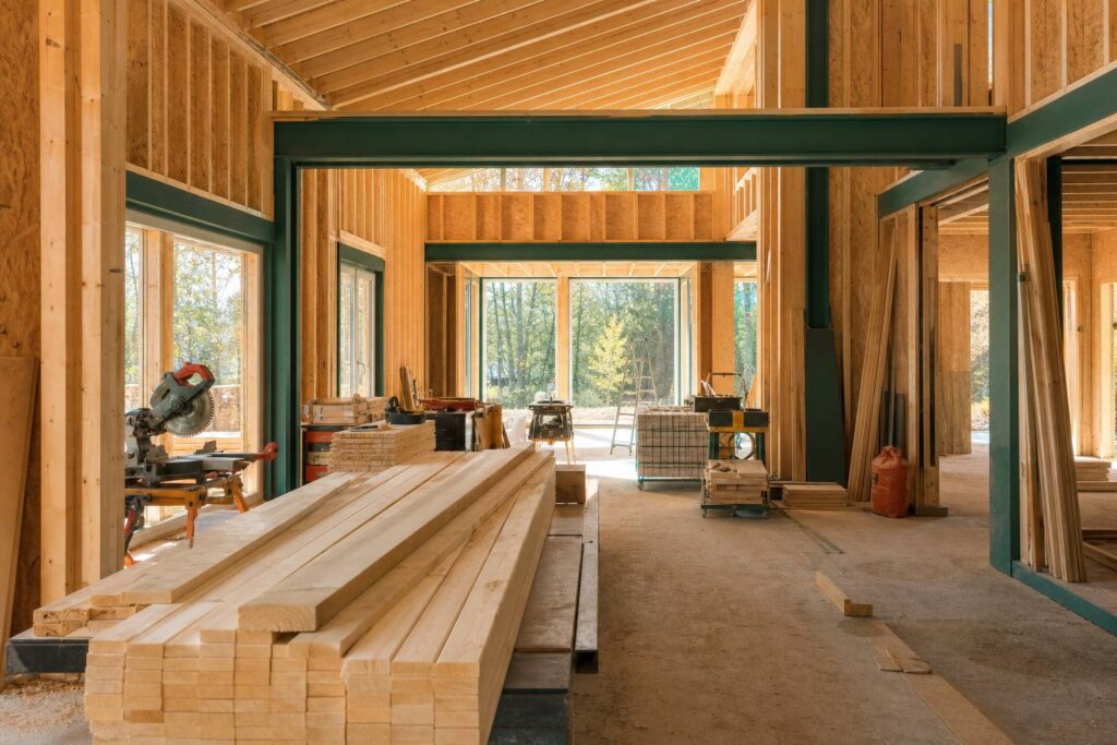 Construction d'une maison en ossature bois avec charpente apparente et lumière naturelle traversant la structure